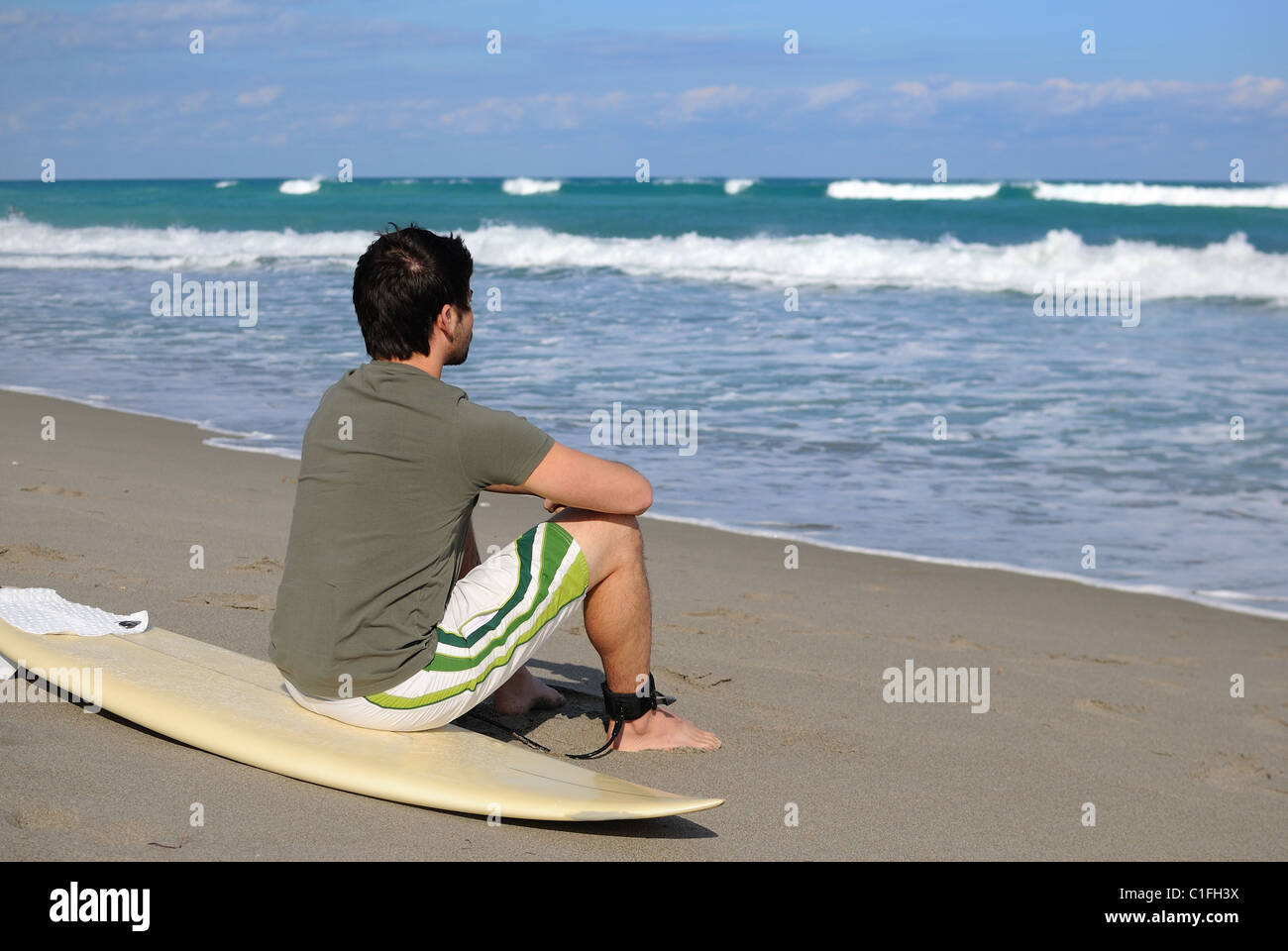 Surfista en la playa con su junta. Foto de stock