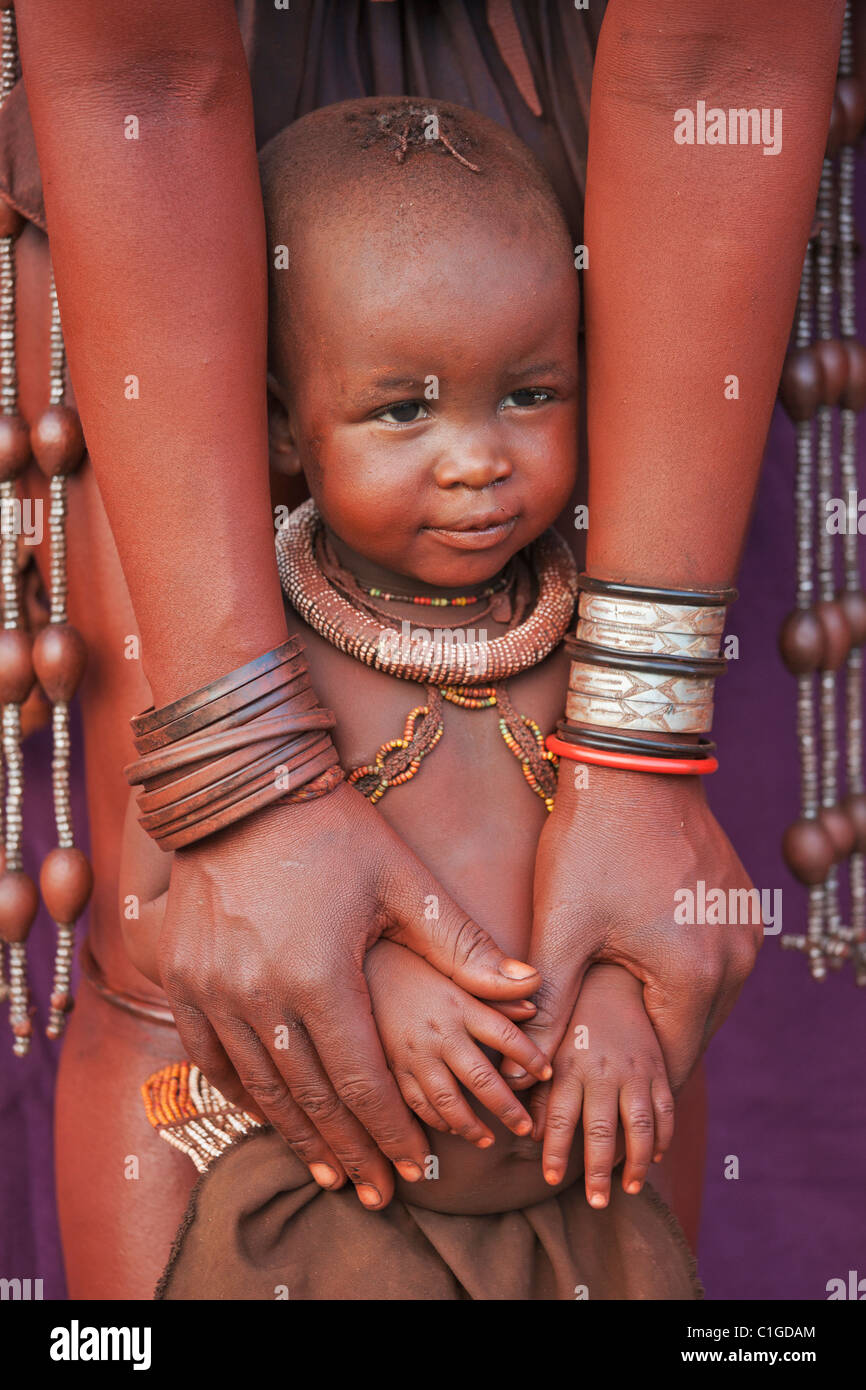 Himbas niño en vestidos tradicionales que viven en la región de Kunene, Namibia Foto de stock