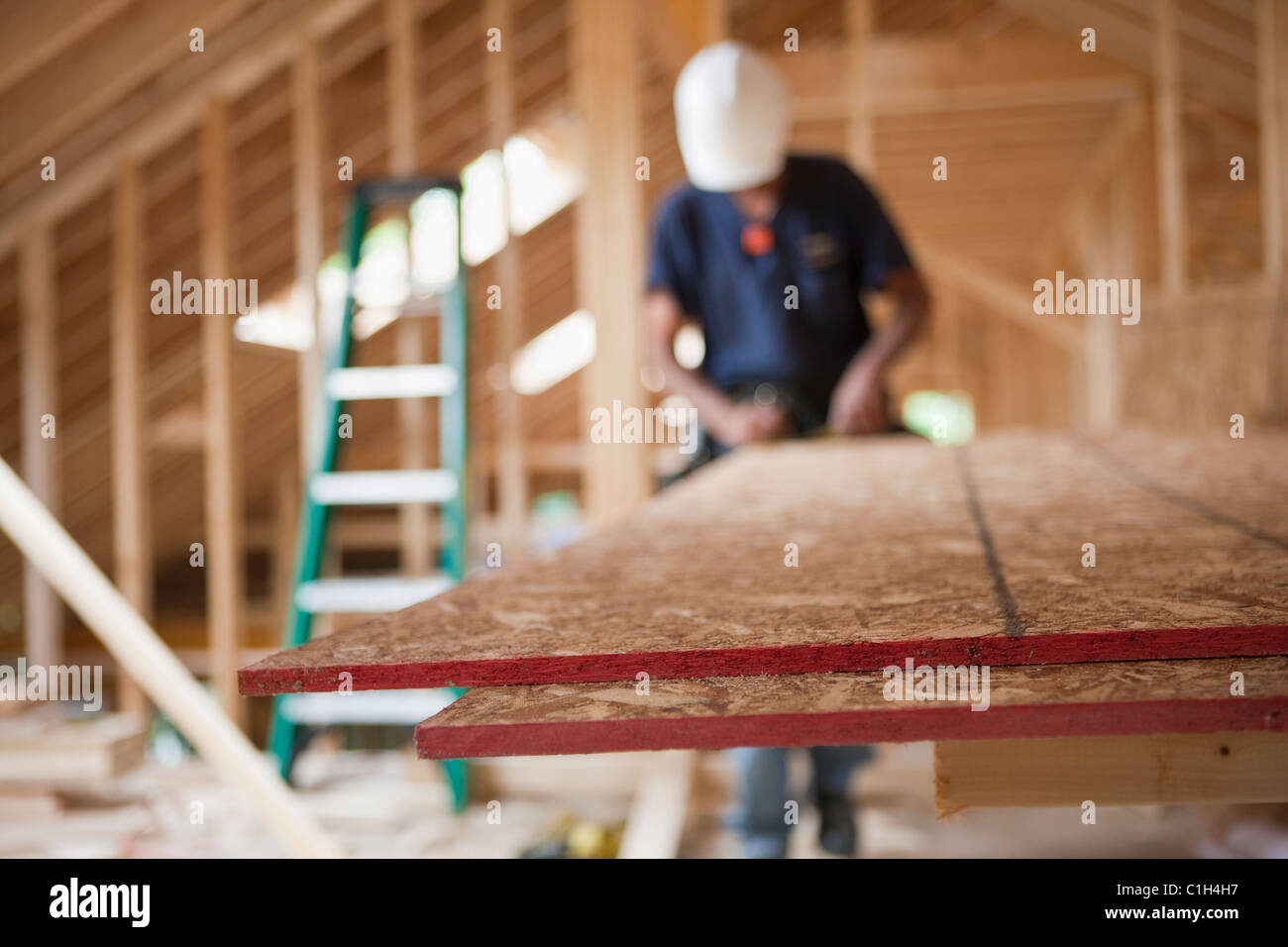 Carpenter usando una sierra circular en tableros de partículas en una casa en construcción Foto de stock