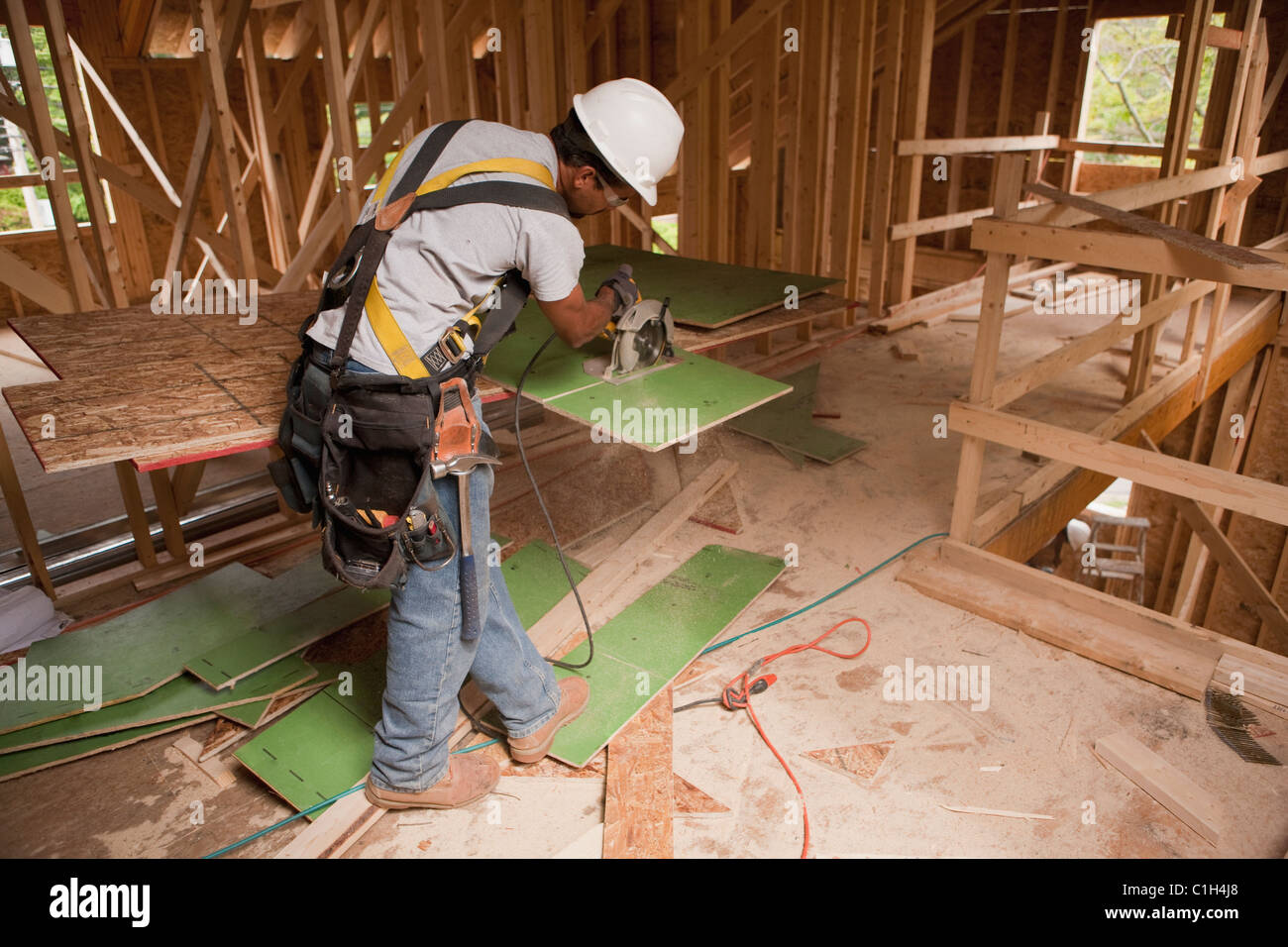 Carpenter usando una sierra circular en el revestimiento de la pared exterior de una casa en construcción Foto de stock