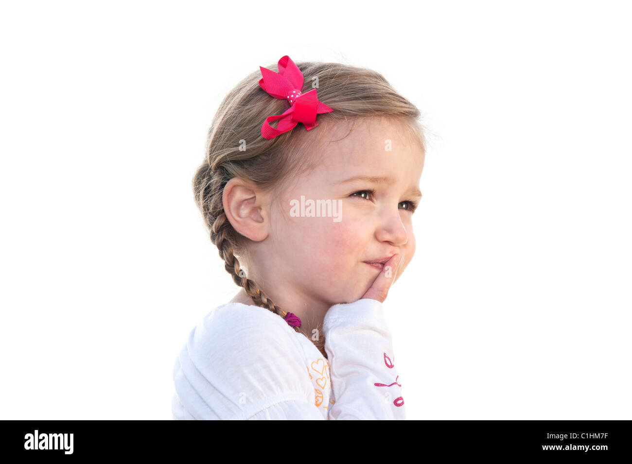 Una pequeña niña de tres años sobre un fondo blanco pensando en algo. Foto de stock