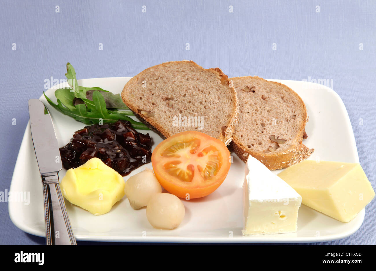 Plowmans almuerzo servido con pan granero fresco y una selección de quesos, tomate fresco, encurtido de cebolla y chutney pickles. Foto de stock