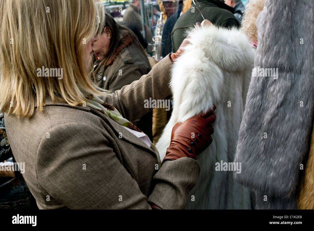 Mujer mirando abrigos de piel a la venta en el mercado de Greenwich Foto de stock