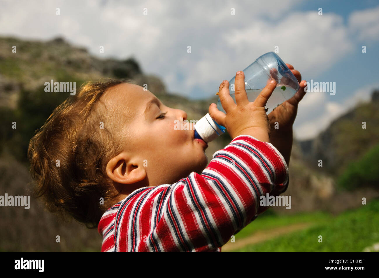 Niño pequeño de 18 meses bebidas desde una botella de agua mineral al aire libre Foto de stock