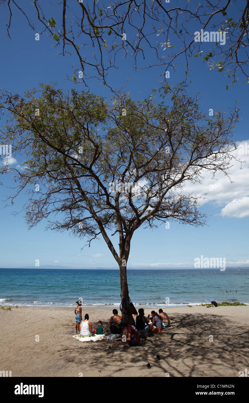 Una familia costarricense en la sombra de un árbol en Playa Panamá, Península de Nicoya, Costa Rica Foto de stock