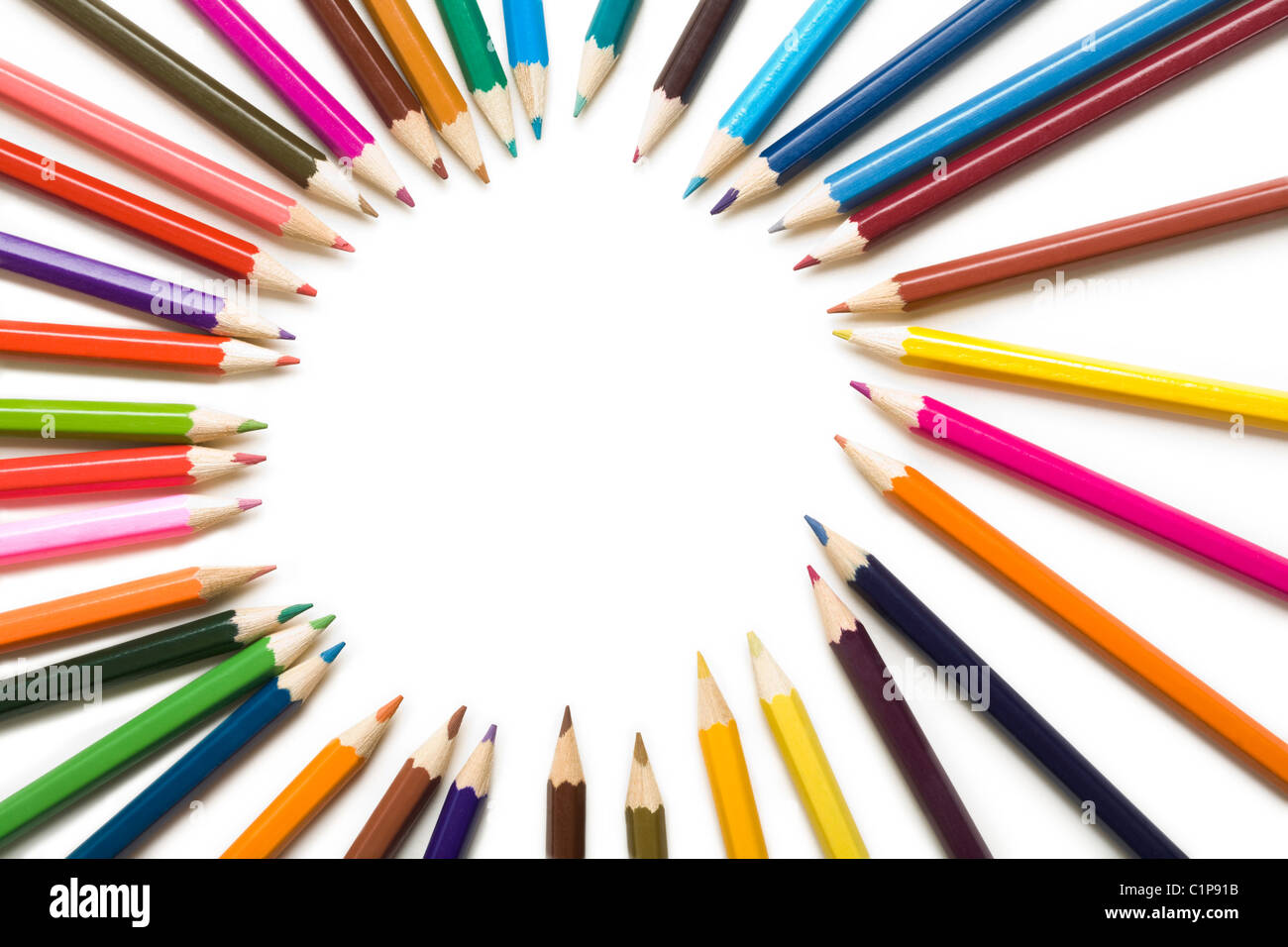 Close-up de coloridos crayones formando ronda sobre fondo blanco. Foto de stock
