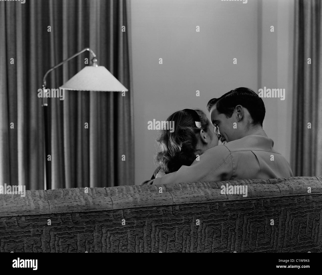 Joven pareja besándose en el sofá, vista trasera Foto de stock