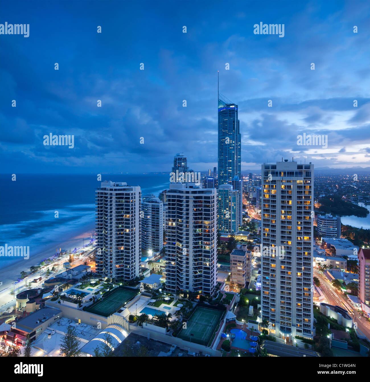 Vistas a la ciudad moderna al anochecer con el océano junto a al formato cuadrado (Gold Coast, Queensland, Australia) Foto de stock