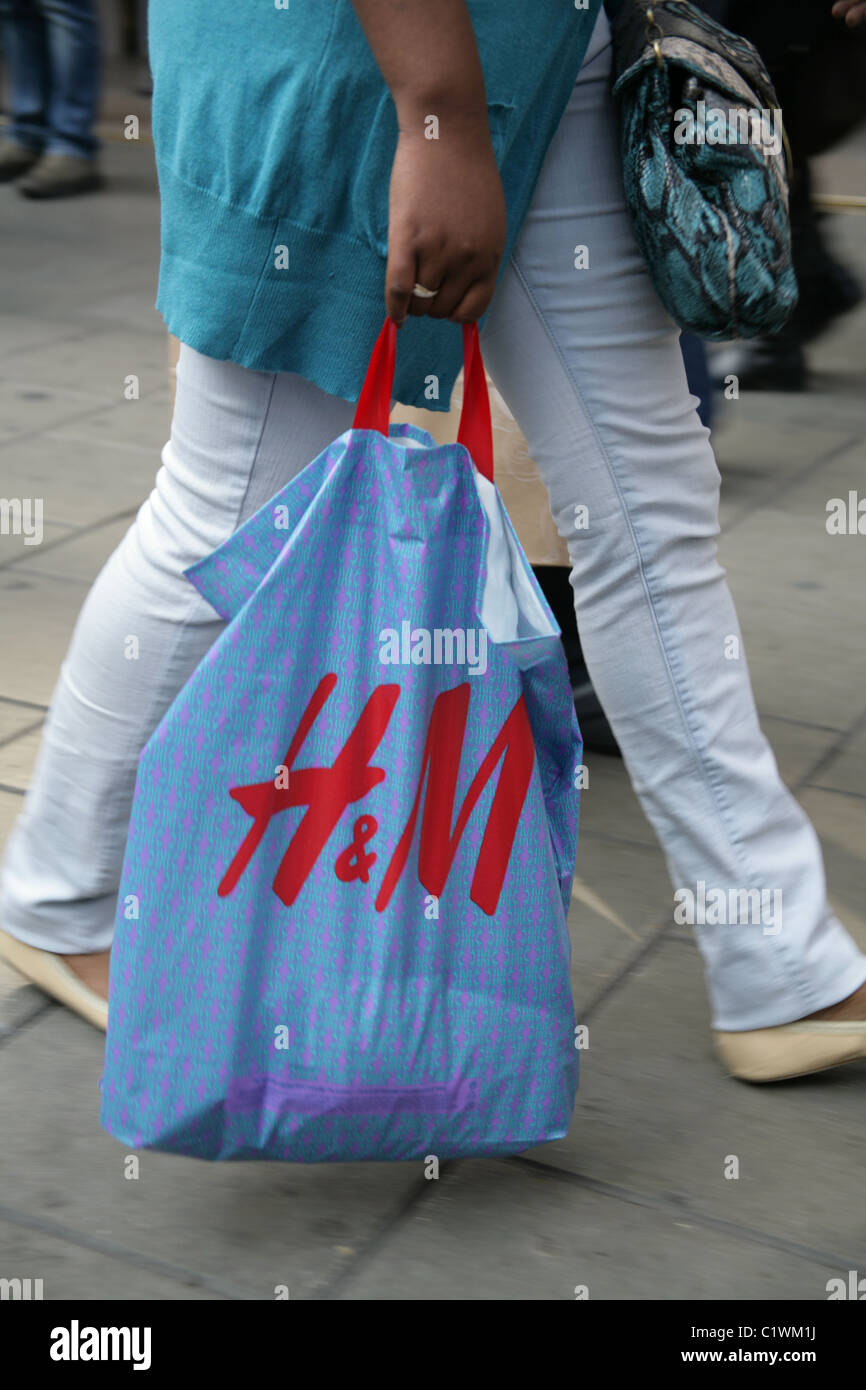 Un comprador en Oxford Street, Londres llevando un H&M (Hennes) bolsa  Fotografía de stock - Alamy
