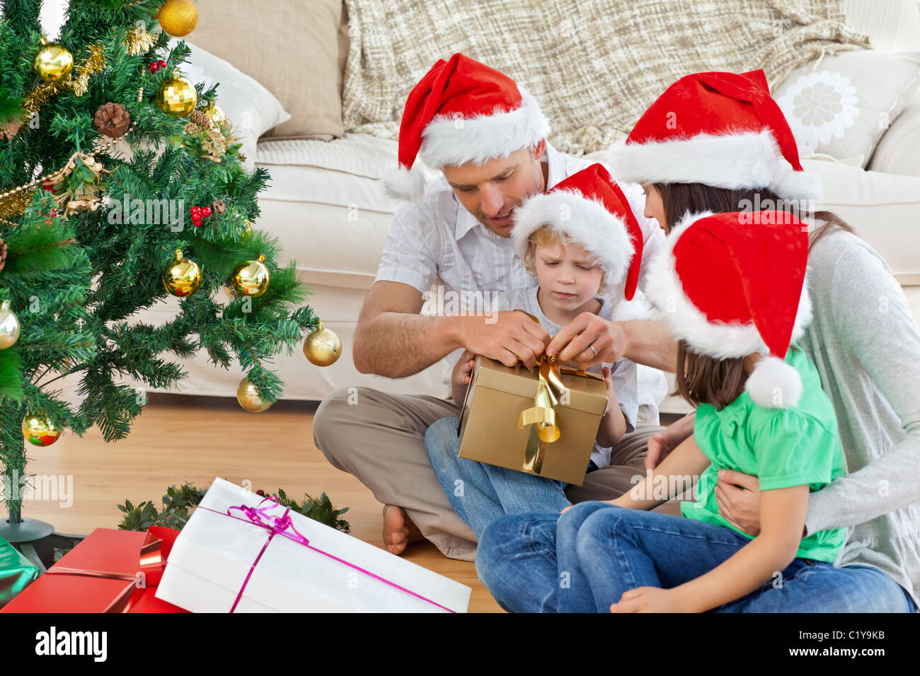 Familia abriendo regalos de Navidad sentados en el suelo Fotografía de  stock - Alamy
