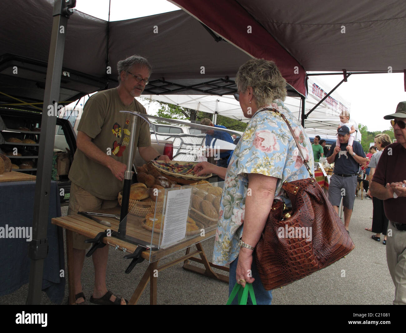 Mujer tratando una muestra de un hombre proveedor en un mercado de granjeros en Austin, Texas. Foto de stock