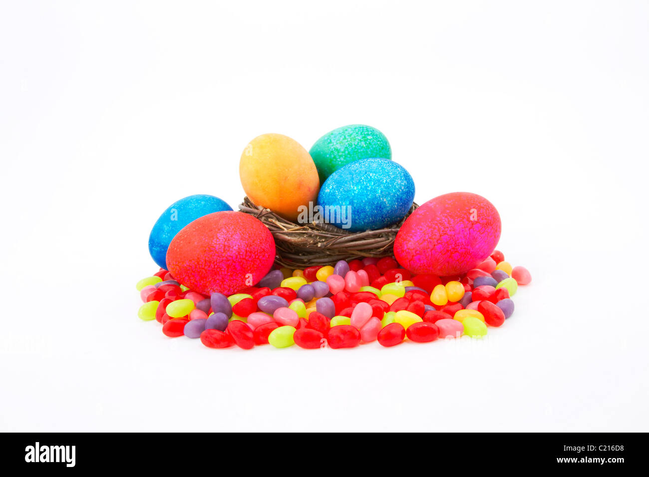 Color moteado, los huevos de Pascua en una ramita natural nido sentarse en coloridos Jelly Beans. Foto de stock