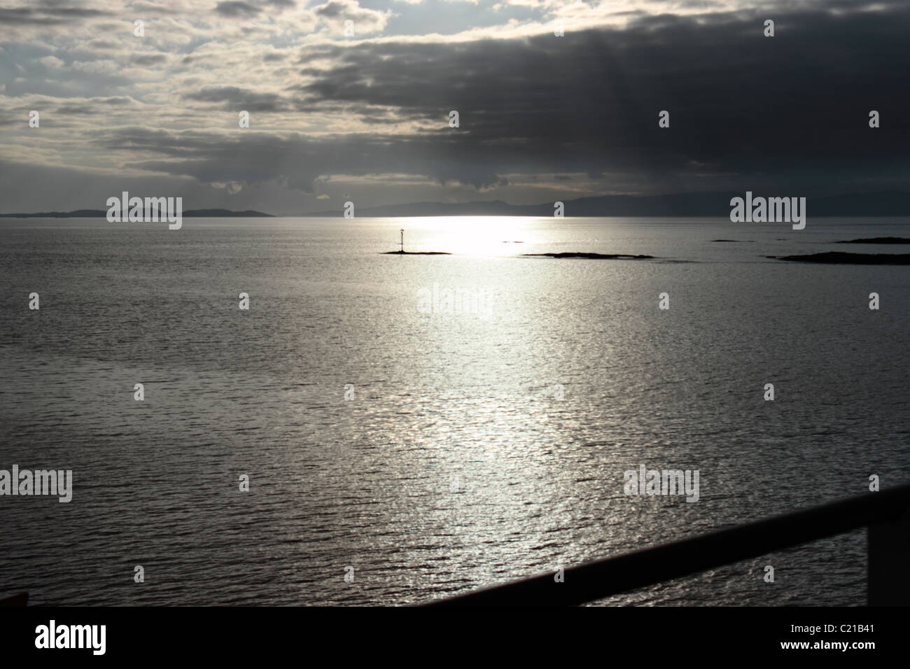 Gris plata puesta de sol sobre las islas de Islay y Jura desde el ferry Calmac Foto de stock