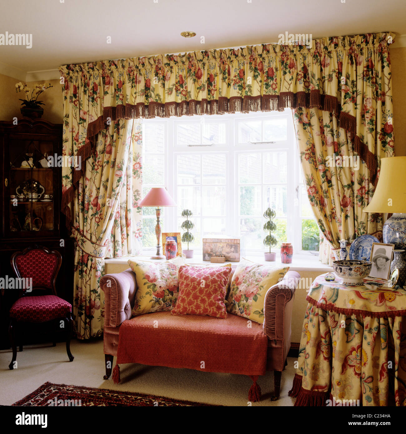 Pequeño sofá delante de una ventana con cortinas floreadas y pelmet  coincidentes Fotografía de stock - Alamy