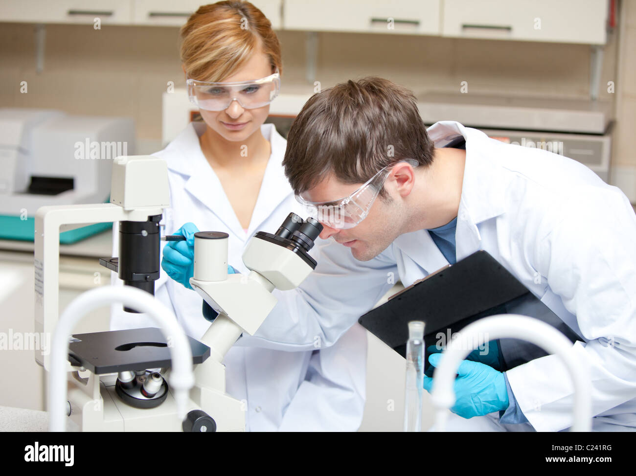 Dos científicos observando algo con un microscopio Foto de stock