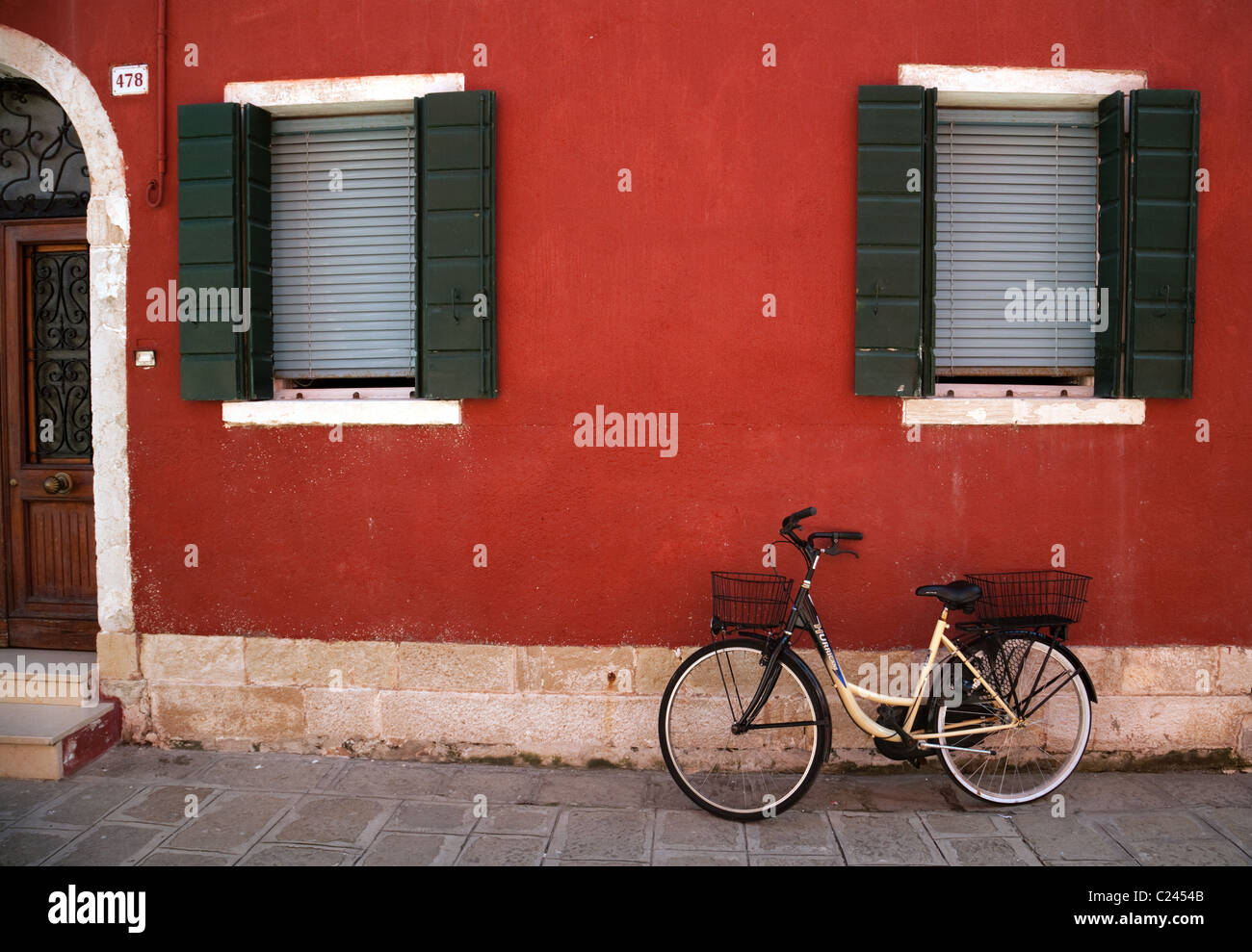 Bicicleta contra una pared roja, Burano village, Venecia Italia Foto de stock