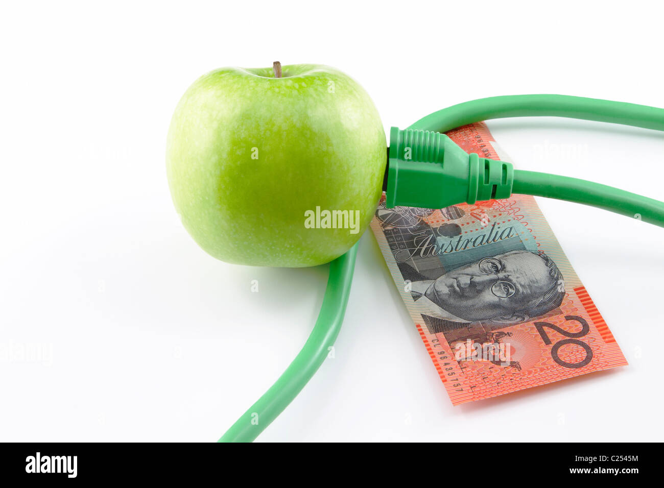 Enchufe eléctrico insertado en manzana verde con moneda australiana; fondo blanco. Foto de stock