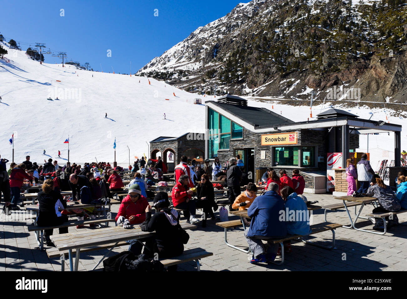 Los esquiadores en la terraza de un restaurante en la montaña Comallempla con las pistas de esquí detrás, Arinsal, la zona de esquí de Vallnord, Andorra Foto de stock