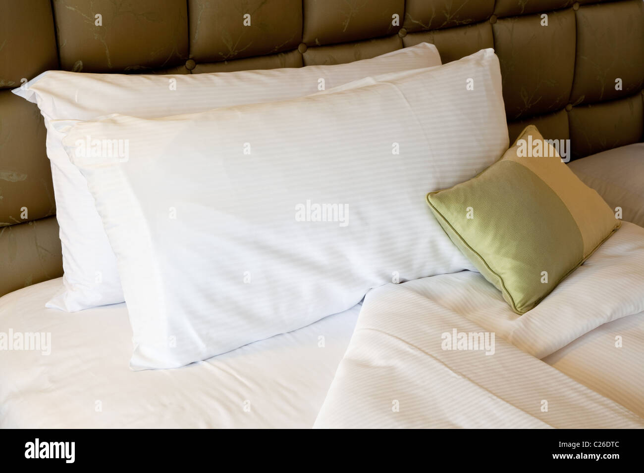 Una cómoda cama con almohadas y edredón cubrir Foto de stock