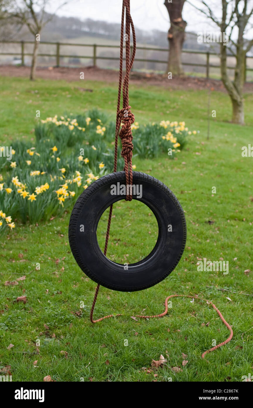 Un neumático neumático swing (swing) configurado para jugar y divertirse en la infancia idílica de un jardín inglés. Foto de stock