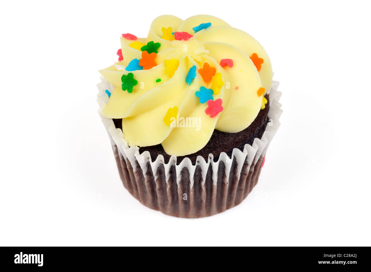 Chocolate cupcake decorado con cobertura de limón amarillo y coloridos rocía sobre fondo blanco cortado Foto de stock