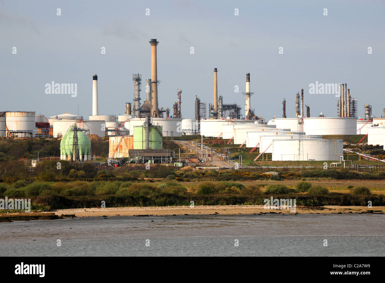 Una refinería de petróleo con chimeneas y grandes tanques de almacenamiento. Foto de stock