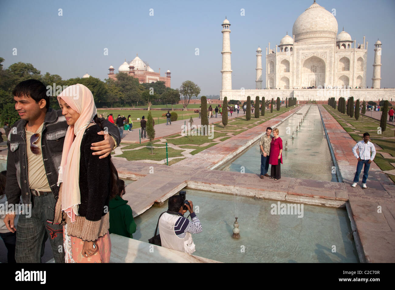 Dos visitantes extranjeros plantean a una foto delante del Taj Mahal, en Agra, India. Foto de stock