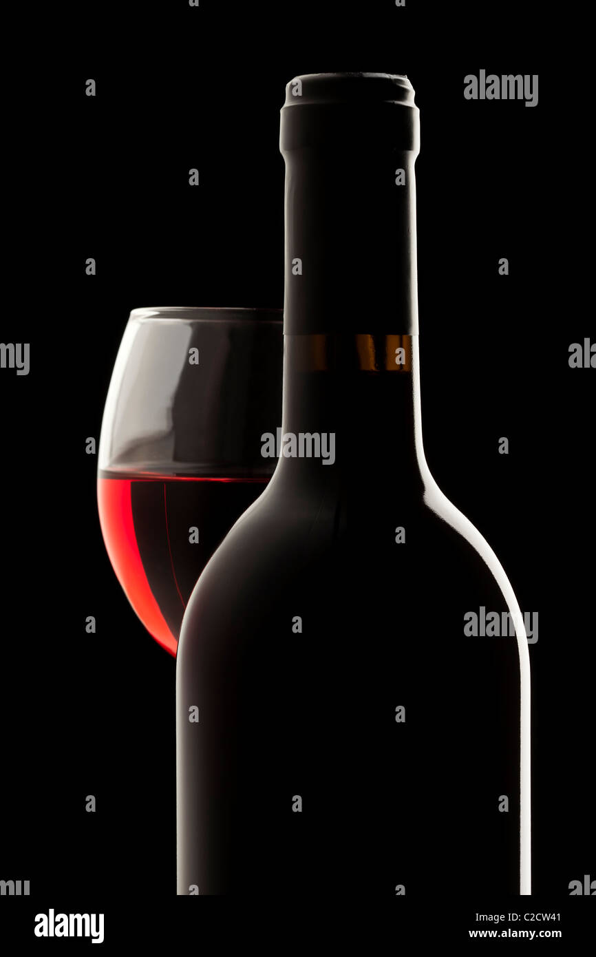 Elegante botella de vino tinto y copa de vino en un fondo negro Foto de stock