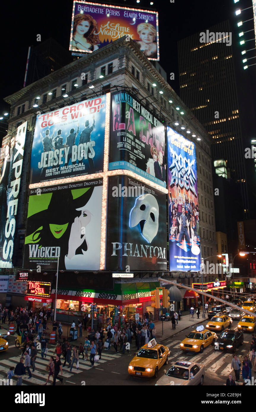 Escena nocturna taxis amarillos y cruce turístico West 47th Street y 7th Avenue con pizzería Sbarro y Phantom Times Square, Foto de stock