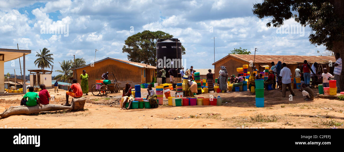 Personas se reunieron junto a una torre de agua con cubos de colores brillantes. Aldea Kisarwe Dar es Salaam Tanzania Foto de stock