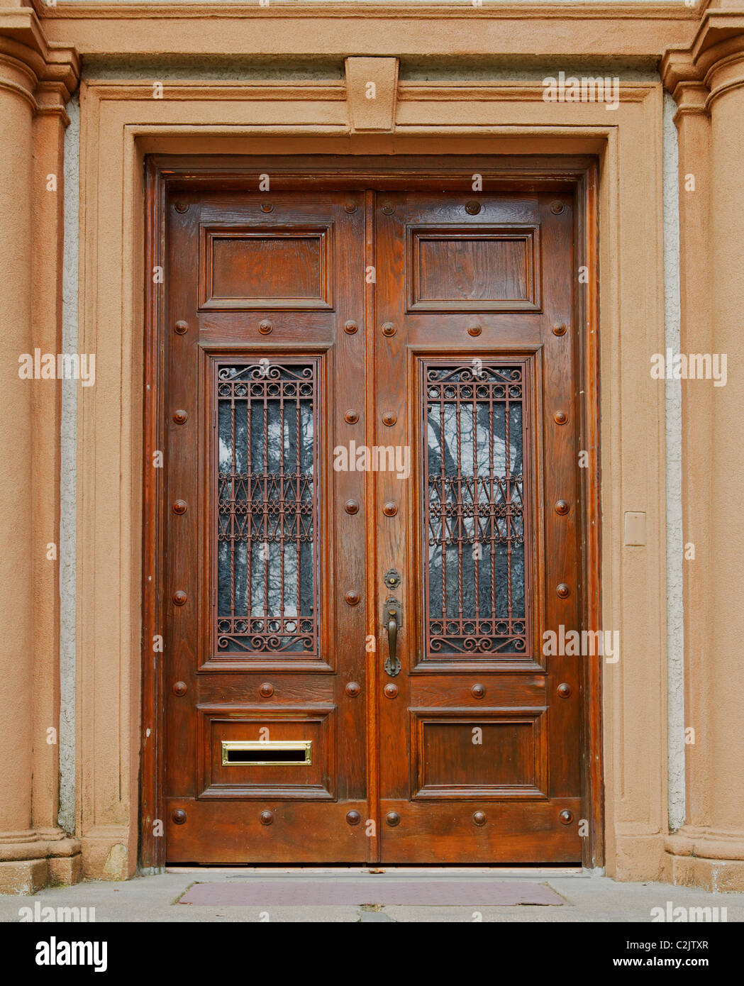Puertas de madera teñida ornamentados con reja de hierro forjado en ventanas  de vidrio Fotografía de stock - Alamy