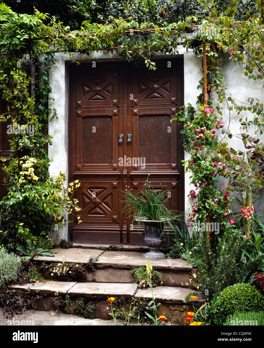 Las grandes puertas de caoba que conduce a un patio jardín pasos en un  jardín de estilo mediterráneo Fotografía de stock - Alamy