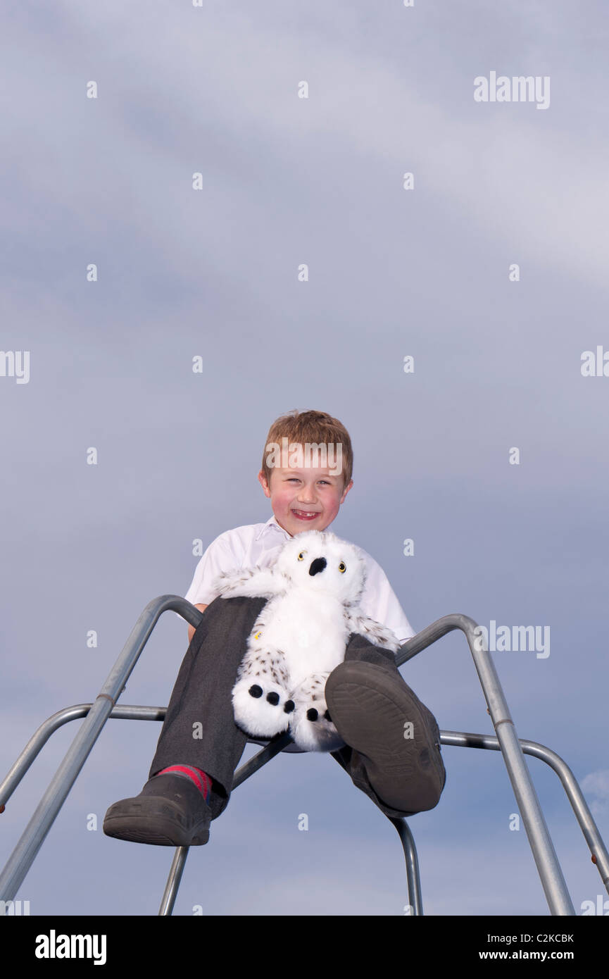 Un modelo liberado imagen de un niño de siete años y su peluche al aire libre en un marco de escalada en el Reino Unido Foto de stock