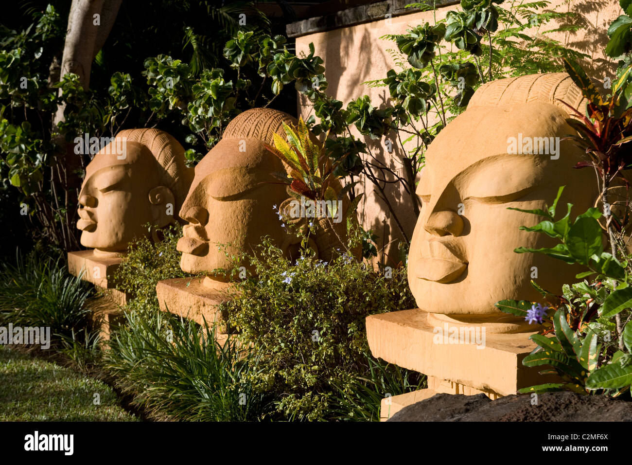 Tres cabezas esculpidas en jardines subtropicales Foto de stock