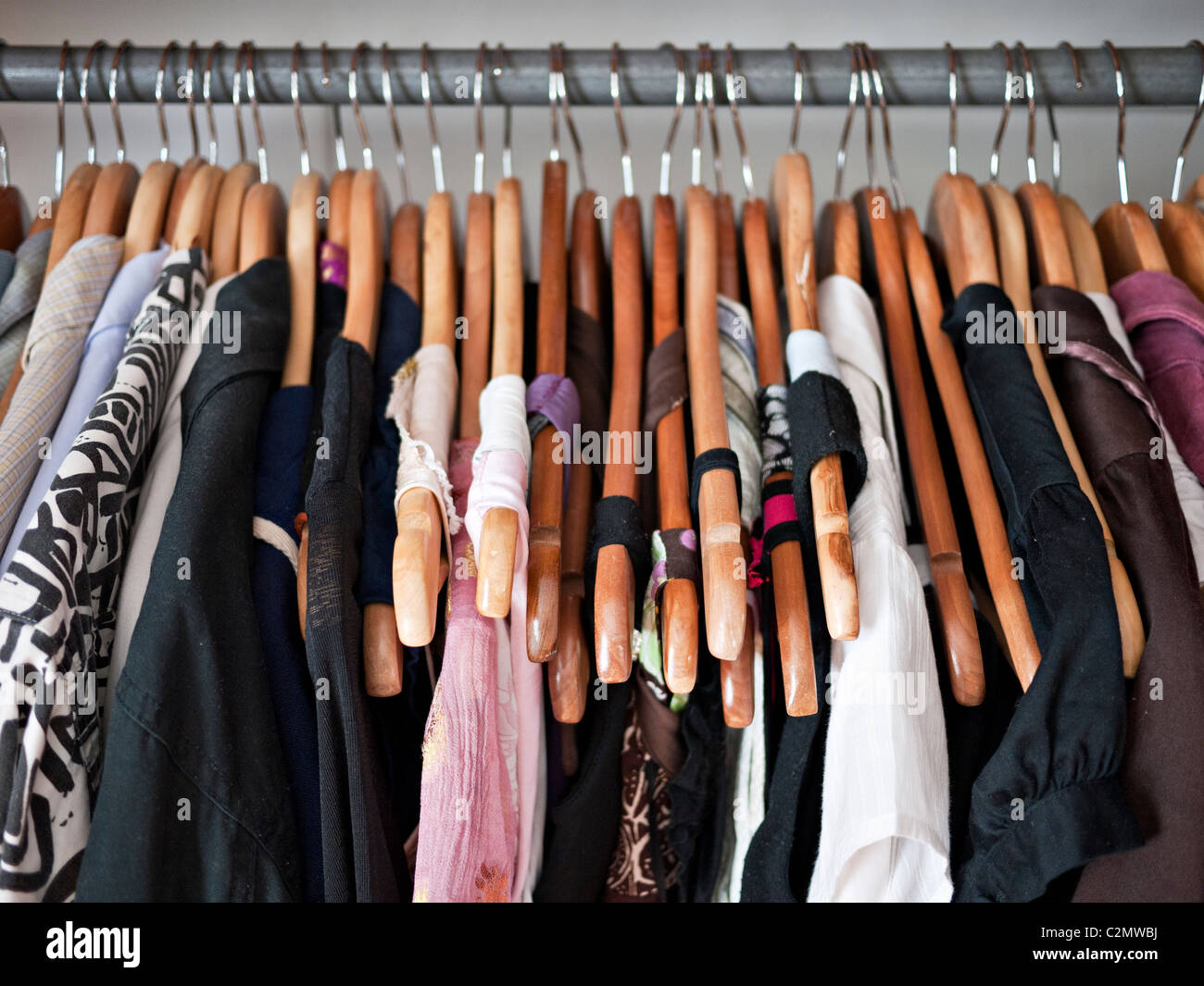 Rampa de ropa en un armario, ropa de hombre y de mujer en perchas de madera Foto de stock