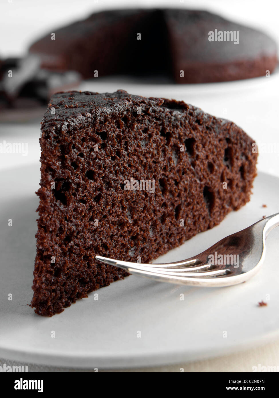 Una rebanada de pastel de chocolate con toda una torta y trozos de  chocolate detrás Fotografía de stock - Alamy