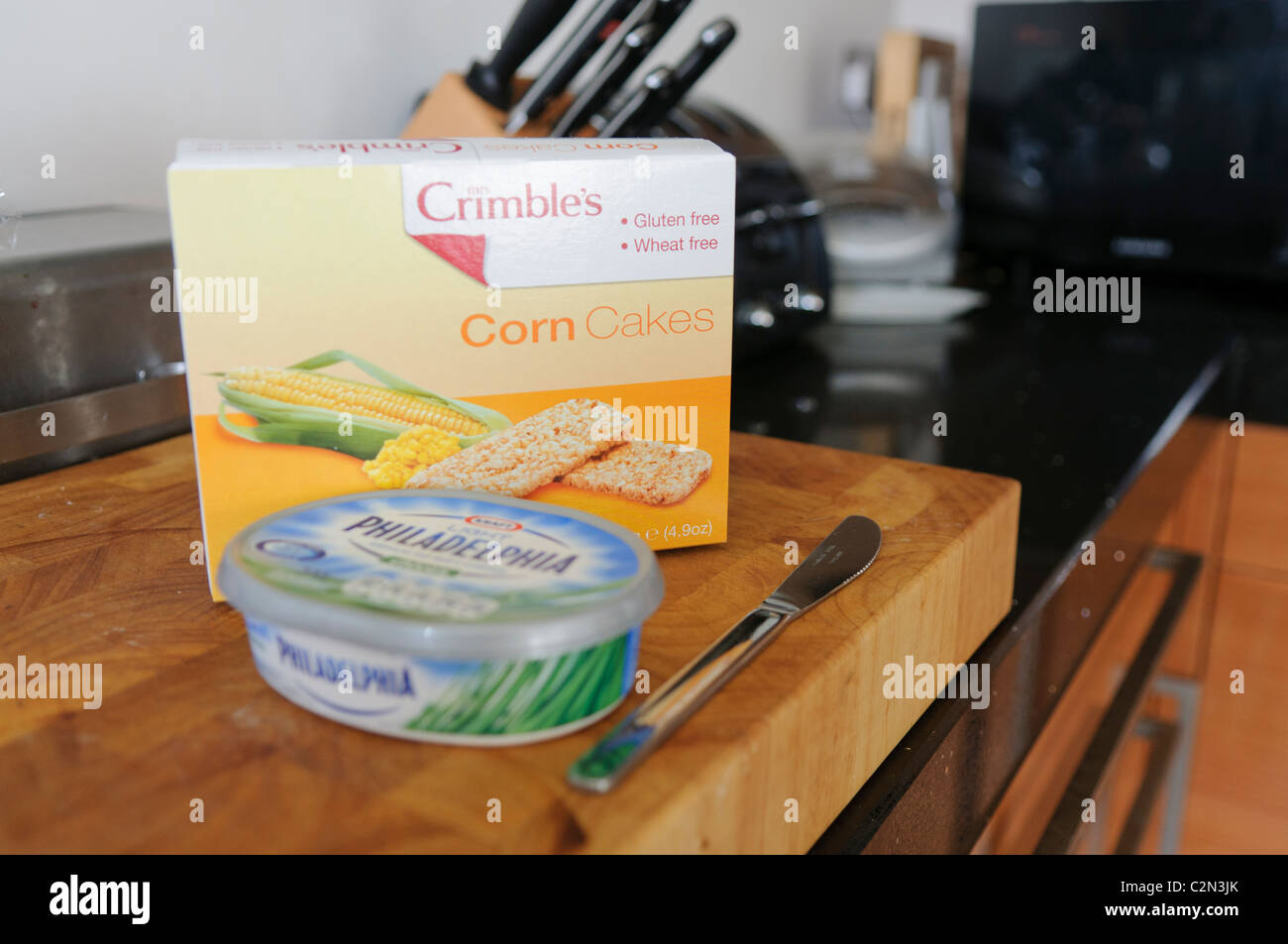 La Crimble sin gluten y trigo tortas de maíz y una bañera de queso crema Philadelphia en un breadboard en una cocina Foto de stock