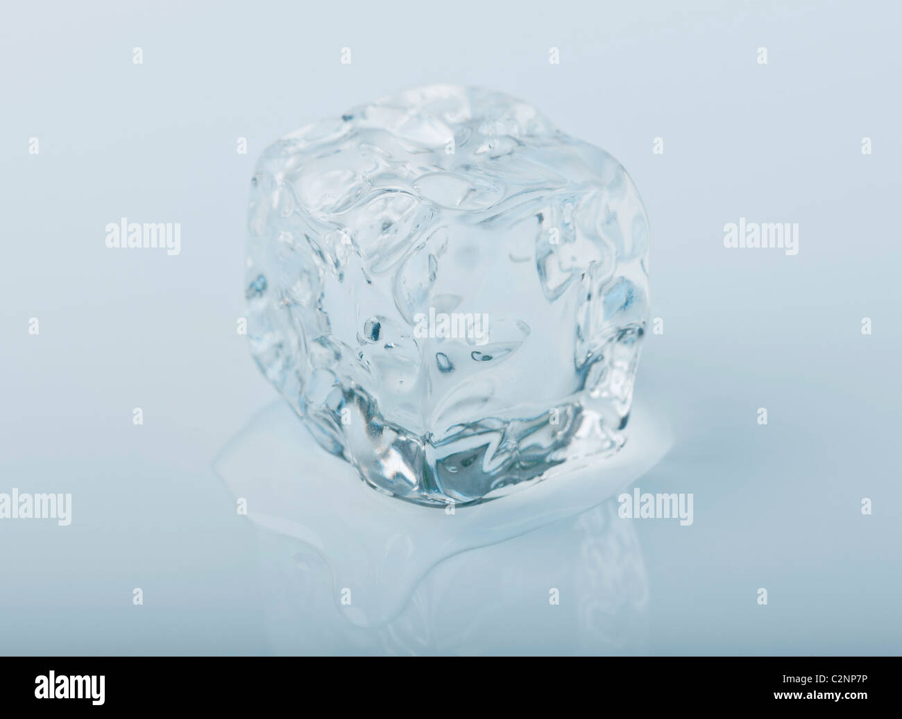 Close-up de un icecube derrite lentamente en un charco de agua Foto de stock