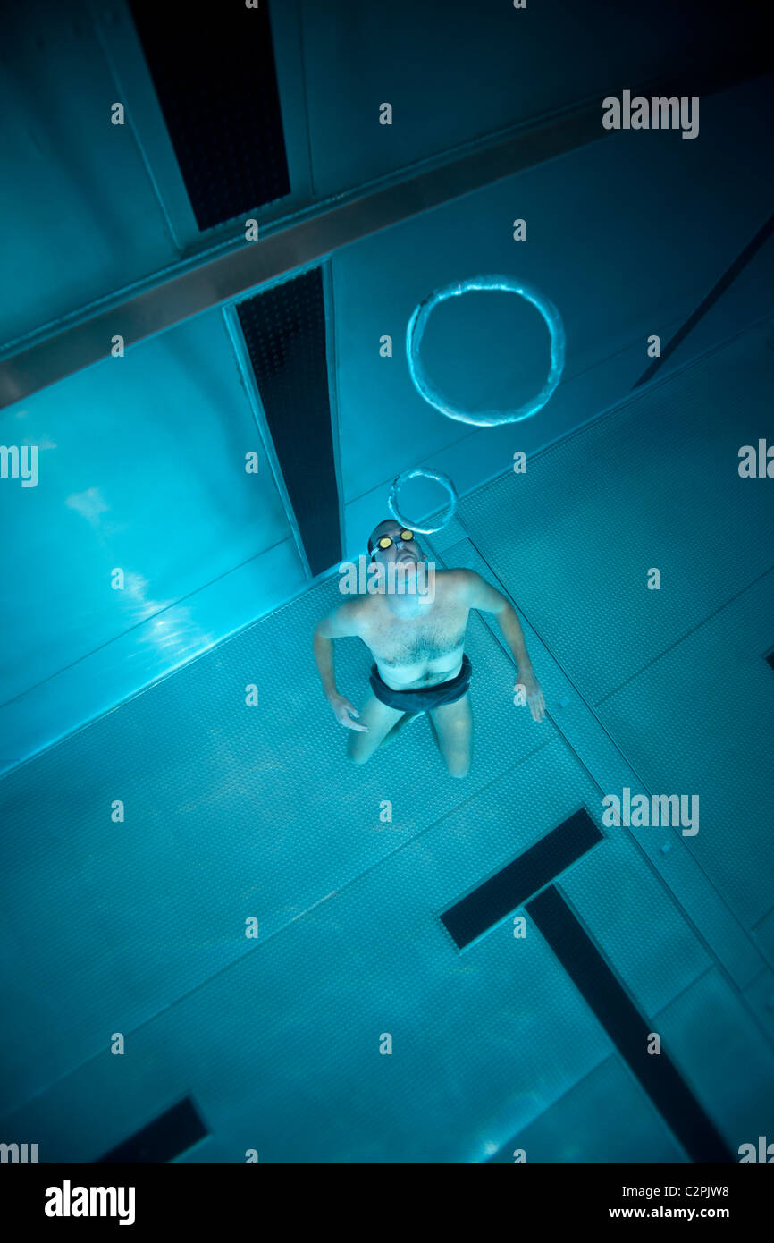 Un nadador generando anillos de burbujas en el fondo de una piscina. Anillo de vórtice, también llamado vórtice toroidal. Foto de stock