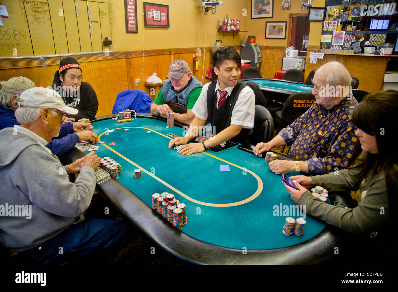 Jugadores de diferentes edades y razas jugar Texas Hold'em poker casino frontal en una tienda en Merced, CA. Foto de stock