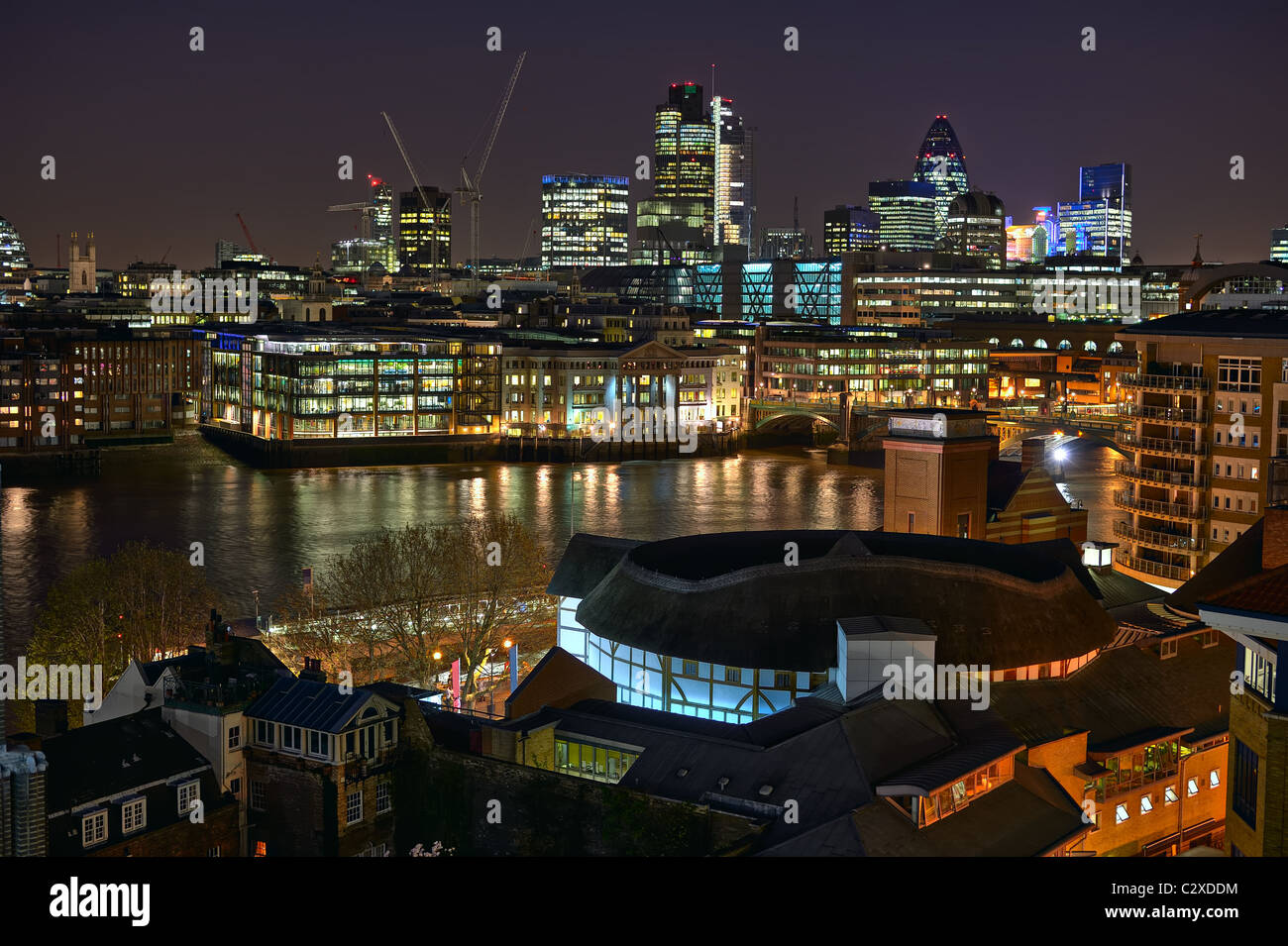Mirando por encima del teatro Shakespeare's Globe y el Río Támesis hacia la ciudad de Londres, Inglaterra, Reino Unido, Europa, por la noche Foto de stock
