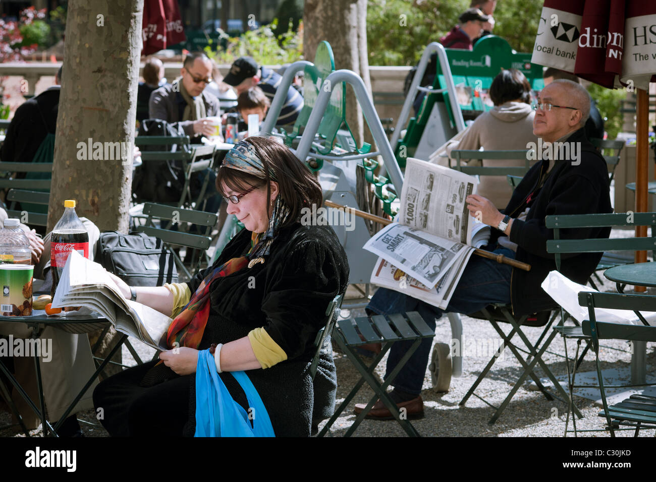 Los visitantes de Bryant Park, en Nueva York, tomar ventaja de periódicos gratuitos en el Bryant Park Sala de Lectura del parque Foto de stock