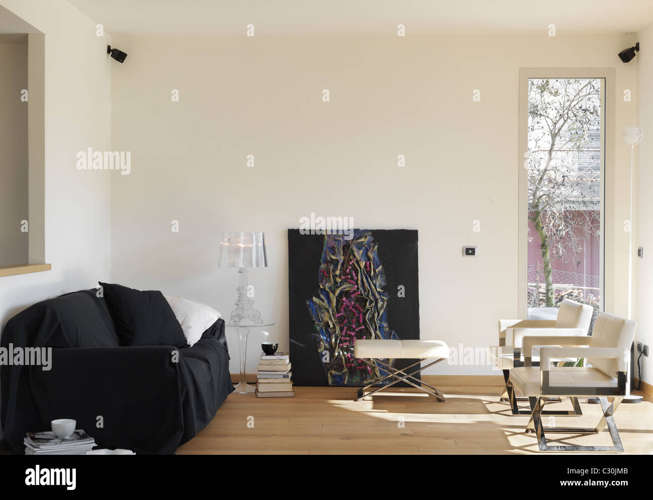 Moderna sala de estar con sofás negros y dos sillones de cuero Foto de stock
