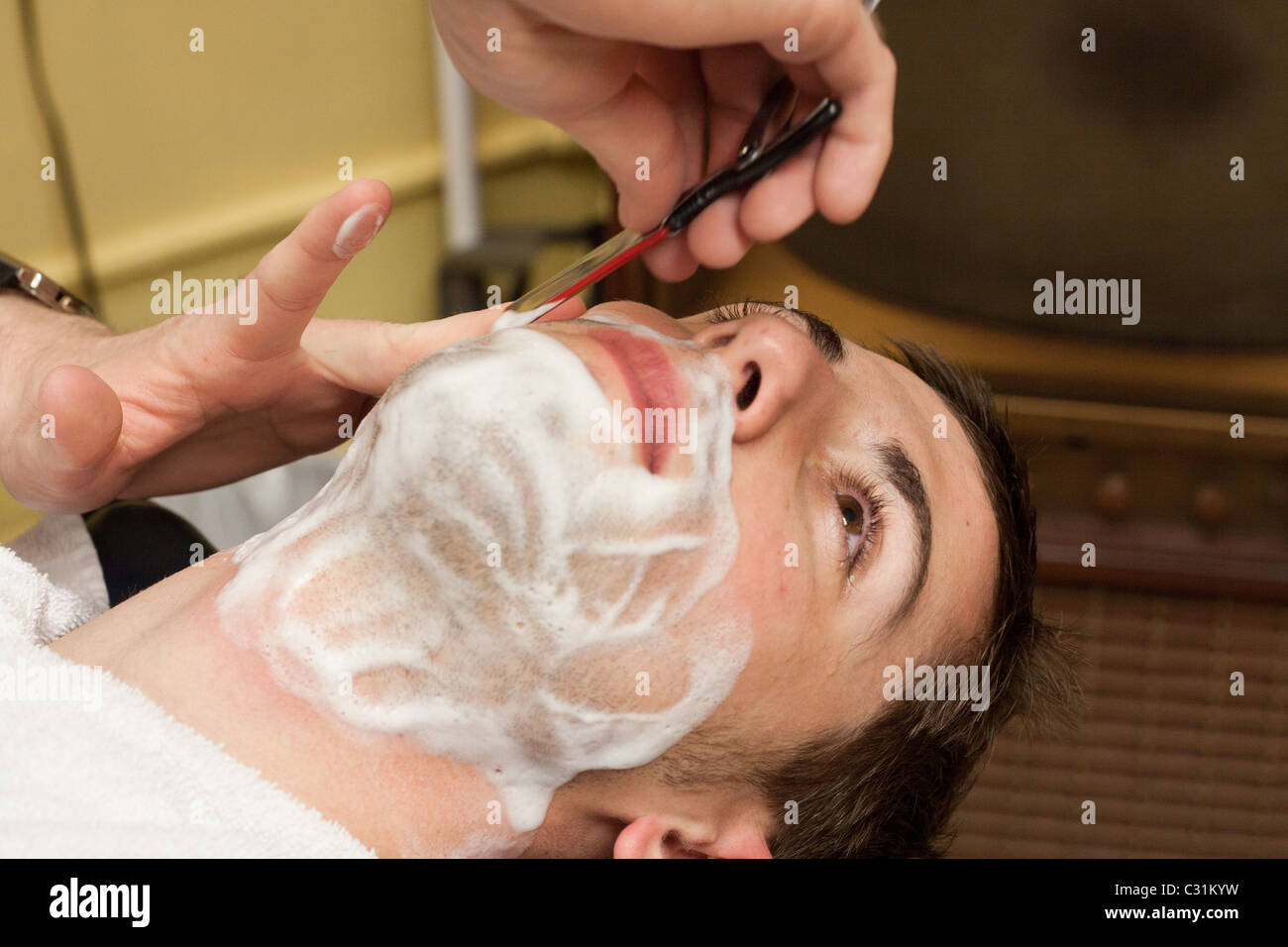 Un hombre recibe un afeitado de una navaja recta en una barbería en Omaha, Nebraska, EE.UU. Foto de stock