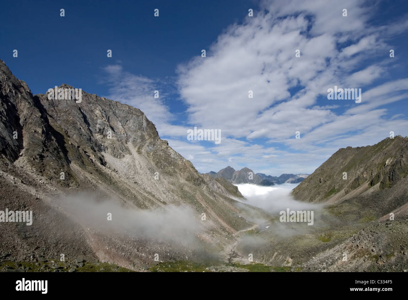 Valle con niebla en las montañas Sayan contra un cielo azul con nubes. Al este de las montañas Sayan. En Siberia. Rusia/ Foto de stock