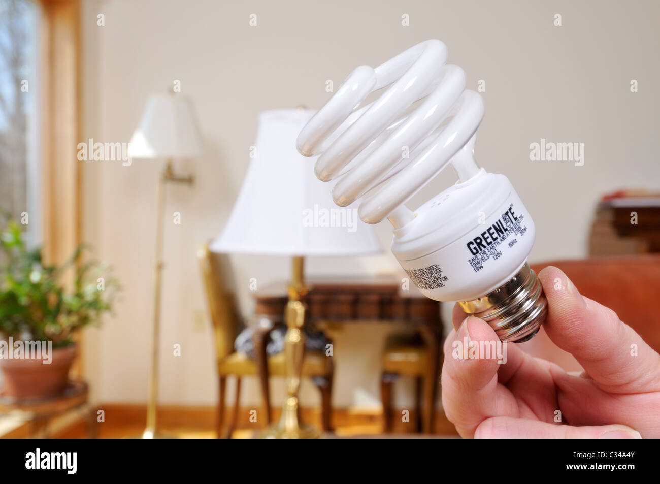 Cambiar las bombillas de luz de una lámpara de una bombilla incandescente a un mayor ahorro energética CFL bulbin habitación de casa. Foto de stock