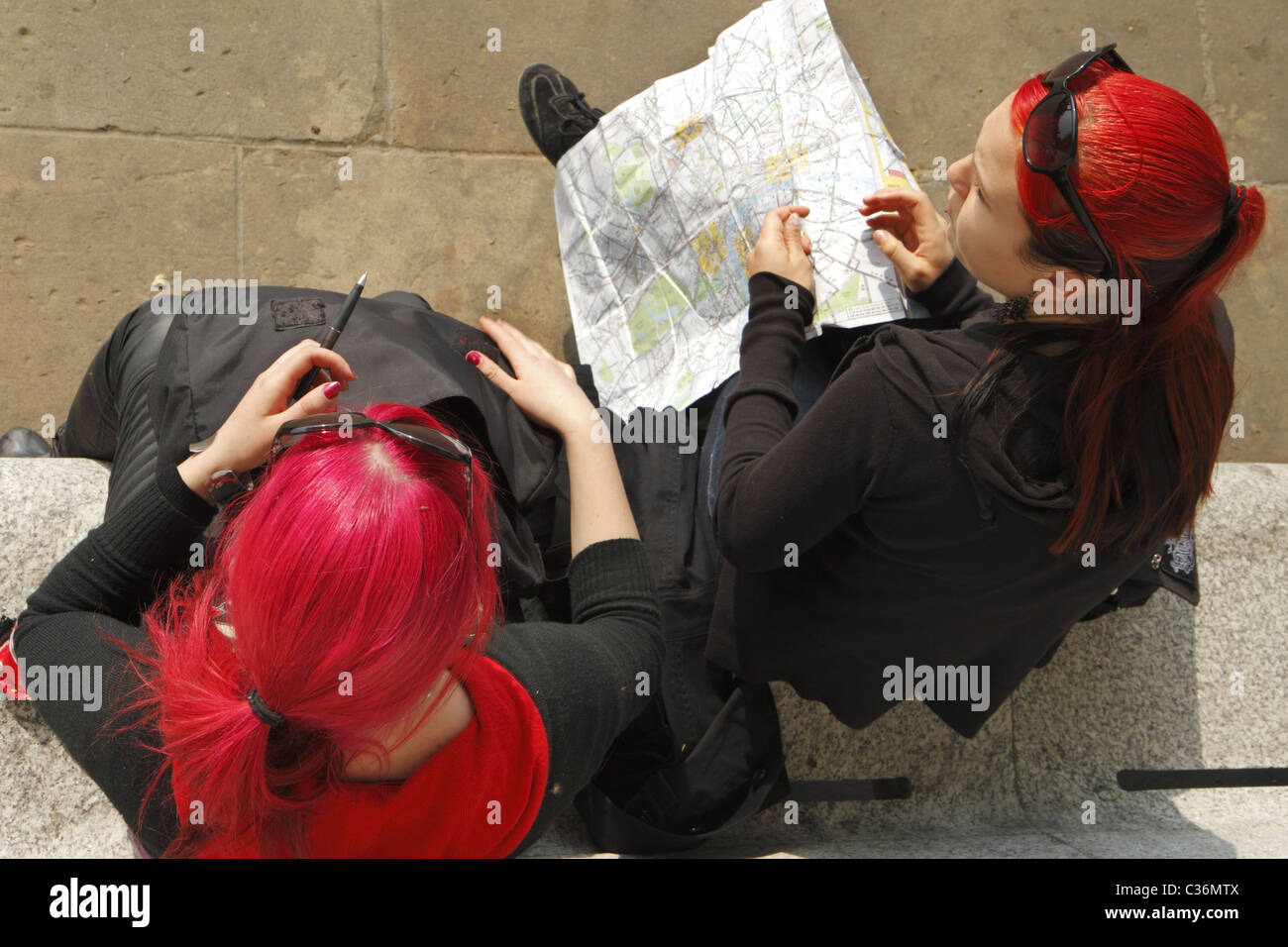 Dos jóvenes mujeres turistas teñida de rojo pelo consultando un mapa, Londres, Reino Unido. Foto de stock