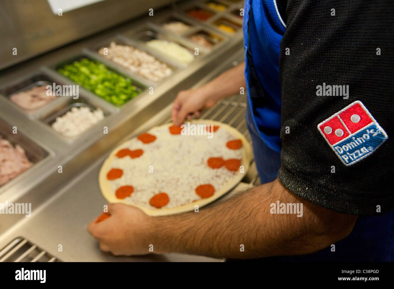 Un empleado de Domino's Pizza preparar una pizza fresca preparada para el  horno de cocción Fotografía de stock - Alamy