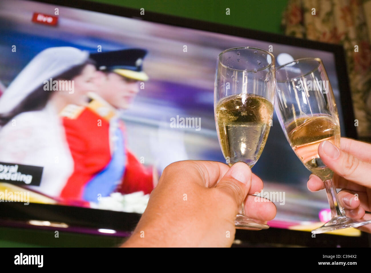 Brindis de champán con la Boda Real en TV en el fondo Foto de stock