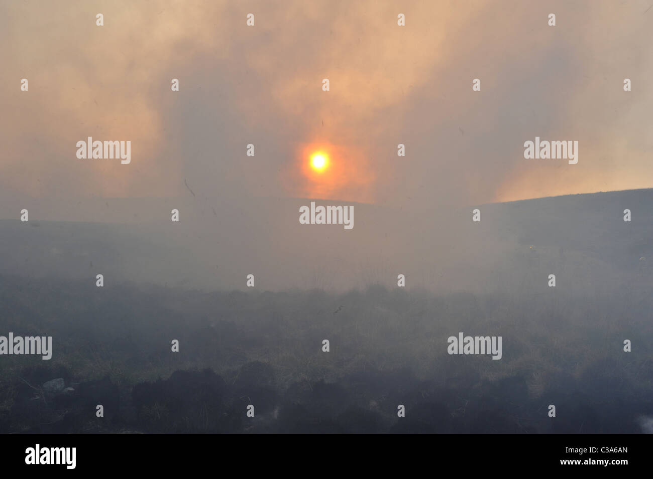 Amanecer a través del humo de los incendios de pasto en páramos en Lancashire, Reino Unido. Foto de stock